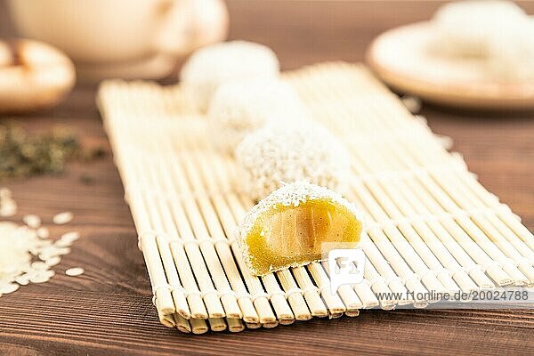 Japanischer Reis süße Brötchen Mochi gefüllt mit Pandan und Kokosnuss Marmelade und Tasse grüner Tee auf braunem Holz Hintergrund. Seitenansicht  Nahaufnahme  selektiver Fokus