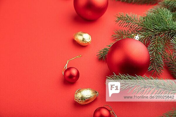 Weihnachten oder Neujahr Zusammensetzung. Dekorationen  rote Kugeln  Tannen und Fichtenzweige  auf einem roten Papierhintergrund. Seitenansicht  Kopierraum  selektiver Fokus