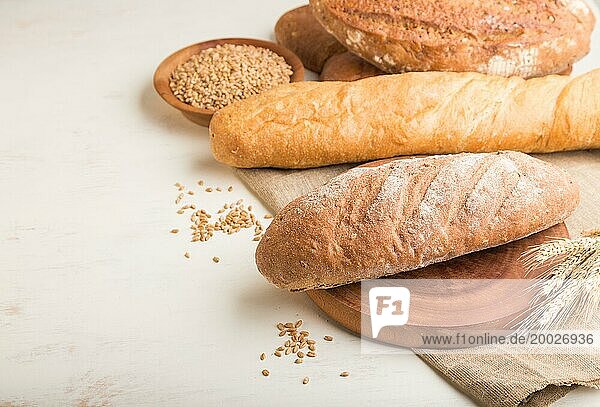 Verschiedene Arten von frisch gebackenem Brot auf einem weißen hölzernen Hintergrund. Seitenansicht  Nahaufnahme  Kopie Raum