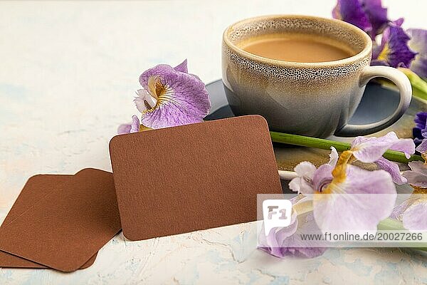 Braune Visitenkarte mit Tasse Kaffee und Irisblüten auf weißem Betonhintergrund. Seitenansicht  Kopierraum  Stillleben. Frühstück  Morgen  Frühling Konzept