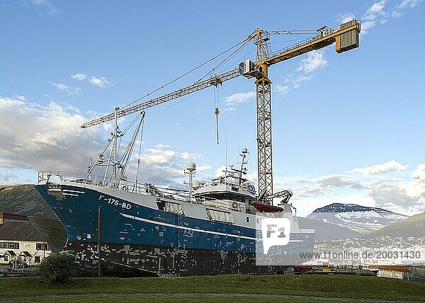 Ein Baukran ragt über ein Fischerboot im Trockendock  Tromso  Norwegen  Europa