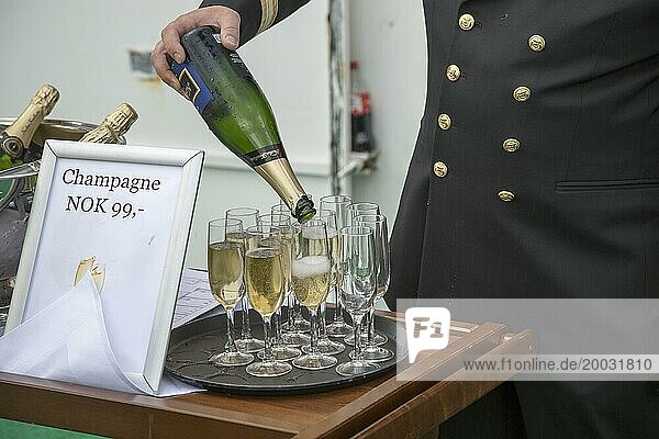 Champagnerfeier bei der Überquerung des Polarkreises in Richtung Süden  Norwegen auf der Hurtigruten Fähre  Offizier schenkt aus der Flasche in Gläser ein