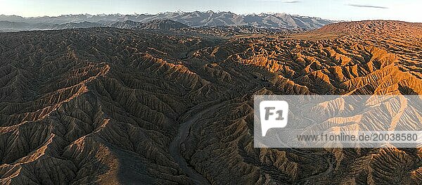 Landscape of eroded hills at Lake Issyk Kul  badlands at sunrise  mountain peaks of the Tien Shan Mountains in the background  aerial view  Canyon of the Forgotten Rivers  Issyk Kul  Kyrgyzstan  Asia