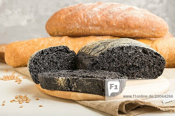 Aufgeschnittenes Schwarzbrot mit verschiedenen Arten von frisch gebackenem Brot auf weißem Holzhintergrund. Seitenansicht  Nahaufnahme  selektiver Fokus