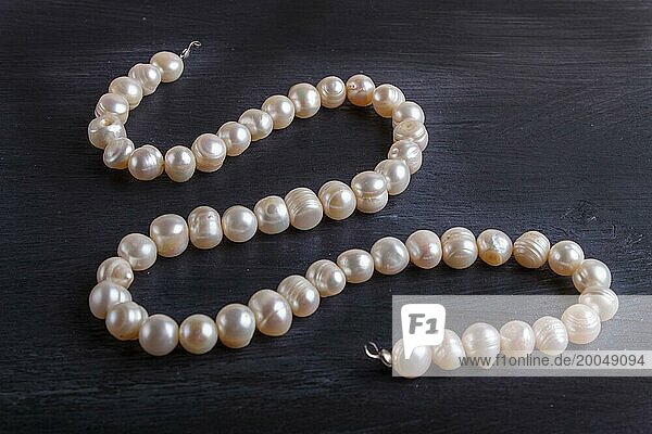 Caramel colored pearl beads on a black background. top view  close up