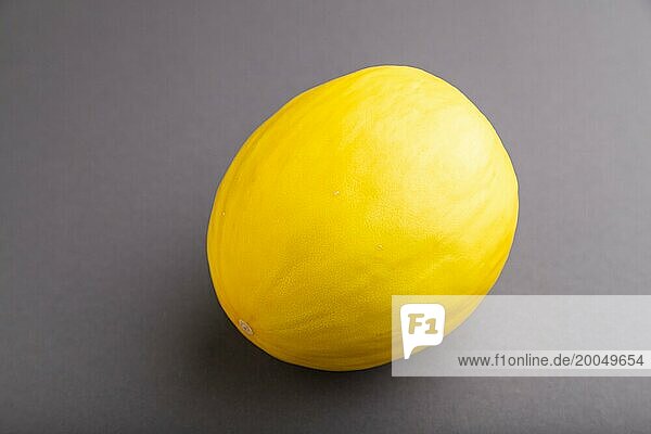 Reife gelbe Melone auf grauem pastellfarbenem Hintergrund. Seitenansicht  Nahaufnahme. Ernte  gesund  vegane Ernährung  Konzept  Minimalismus
