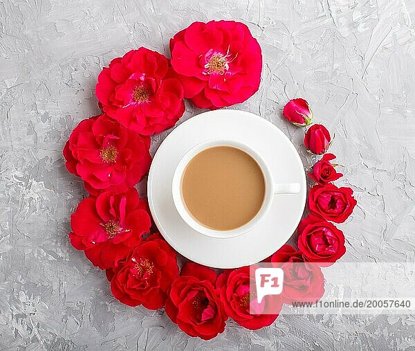 Red rose flowers in a spiral and a cup of coffee on a gray concrete background. Morninig  spring  fashion composition. Flat lay  top view  close up