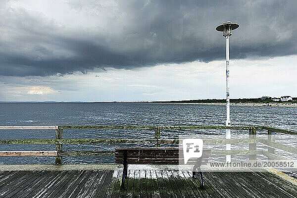 Bank auf einem maroden Steg an der Ostseeküste  Meer  Ostsee  Urlaub  düster  depressiv  niemand  leer  stürmisch  schlechtes Wetter  bewölkt  Wolken  Regenwolken  Aussicht  Stimmung  Atmosphäre  Deutschland  Europa