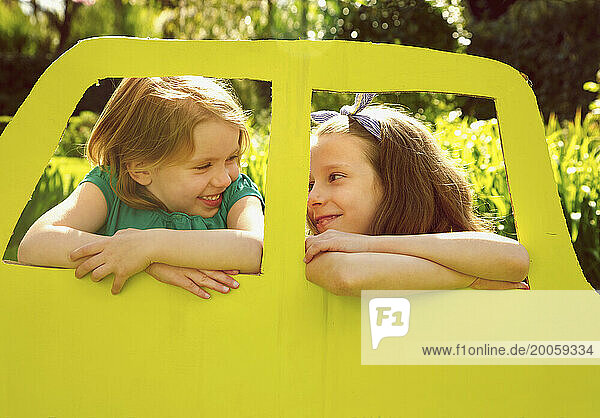 Young Girls Leaning out of Cardboard Car Window