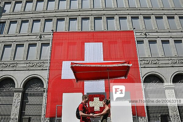 Ein verliebtes Paar vor der riesigen Schweizer Fahne bei der Nationalbank am Nationalfeiertag auf dem Bürkliplatz in der Stadt Zürich
