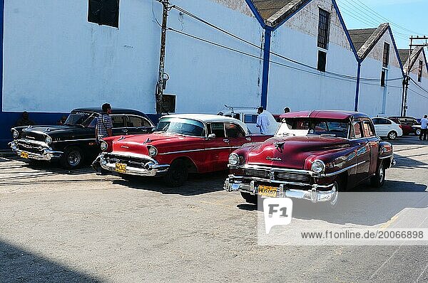 Drei Oldtimer vor der Hafen Lagerhalle in Havanna parkiert. Drei kubanische Oldtimer parken vor der Hafen Lagerhalle in Havanna
