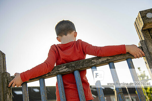 Young boy leaning on a railing.