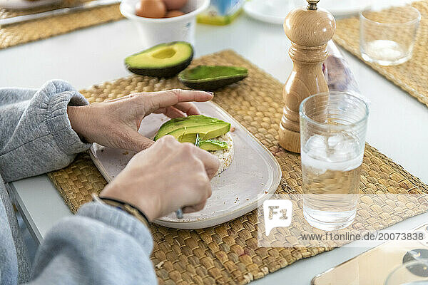 Blonde attractive girl eating a healthy breakfast of avocado