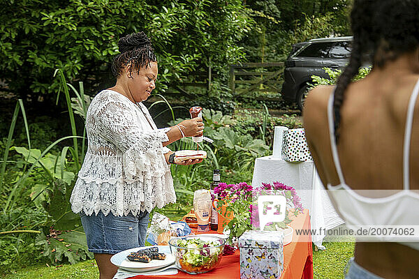 Women enjoying a summer BBQ garden party cooking and eating outside