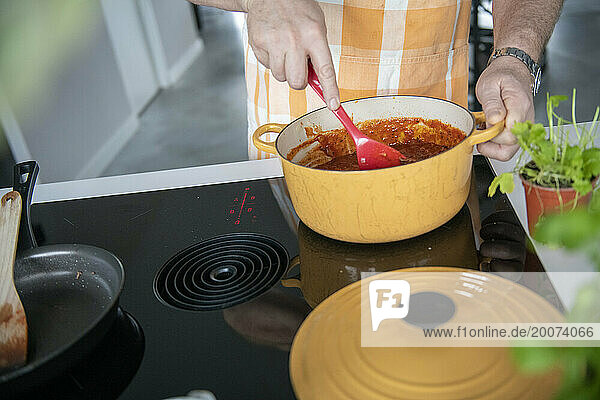 Adult man preparing mince for a lasagne in his modern kitchen