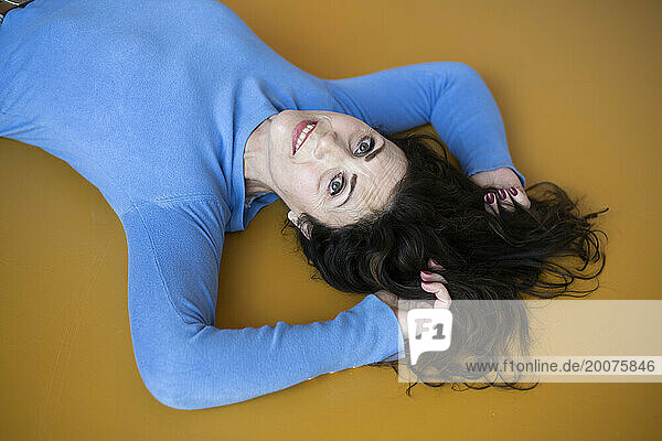 Attractive woman laying down with her hands above her head  her hair sprayed out and looking relaxed