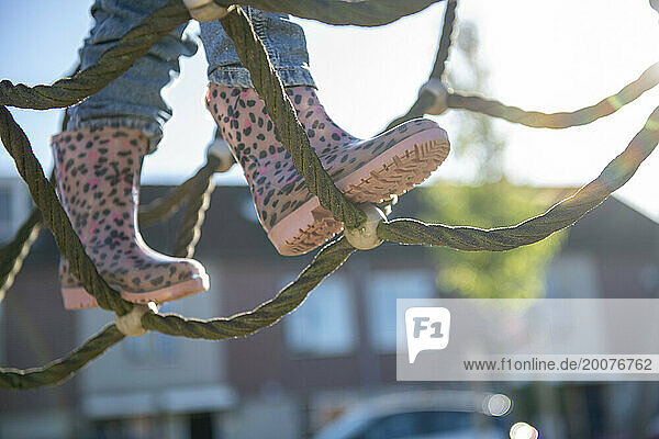 Little girl being brave climbing through a adventure playground in public park