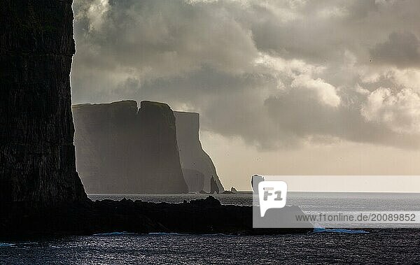 Zerklüftete Steilküste der Färöer Inseln mit dramatisch bedecktem Himmel