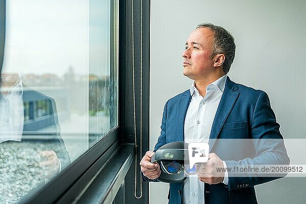 Geschäftsmann  der mit einer futuristischen Virtual Reality Brille durch das Fenster schaut und sich auf eine erfolgreiche Zukunft konzentriert