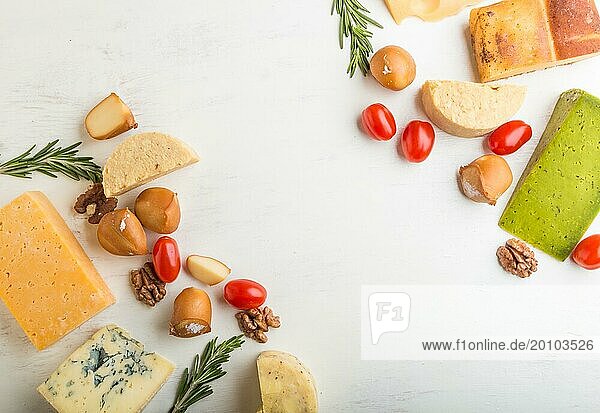 Set of different types of cheese with rosemary and tomatoes on a white wooden background. Top view  flat lay  copy space