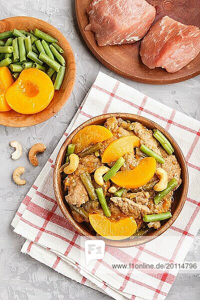 Fried pork with peaches  cashew and green beans on a black concrete background. top view  close up  flat lay  chinese cuisine. linen textile