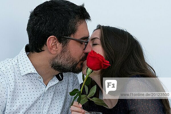 Junges Paar  das sich küsst und eine rote Rose vor sich hat