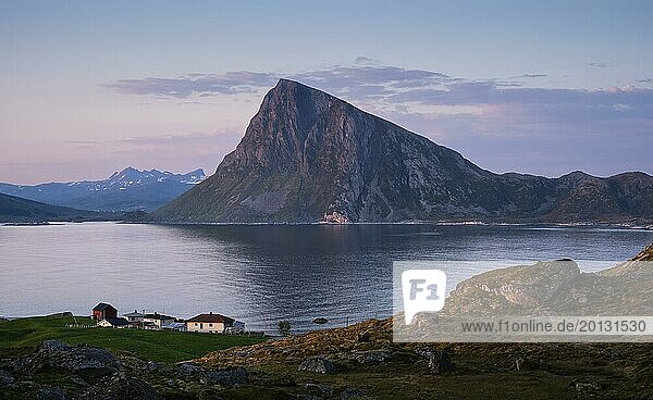 Landscape at Stornappstinden mountain. View of the mountain Offersoykammen on Vestvagoya. Some houses in the foreground. At night at the time of the midnight sun in good weather. Early summer. Flakstadoya  Lofoten  Norway  Europe