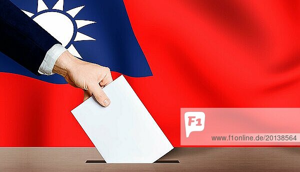 Hand hält Stimmzettel in Wahlurne mit Taiwan Flagge im Hintergrund. Taiwan Präsidentschaftswahlen
