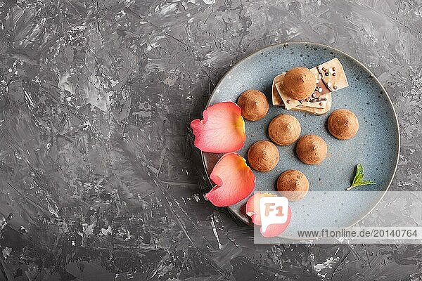 Chocolate truffle on blue ceramic plate decorated with rose petals on black concrete background. close up  top view. copy space