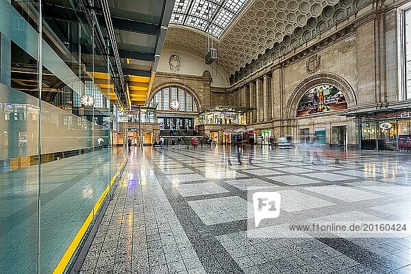 Light floods the waiting hall of a railway station with shiny floor tiles and reflections  Leipzig Central Station