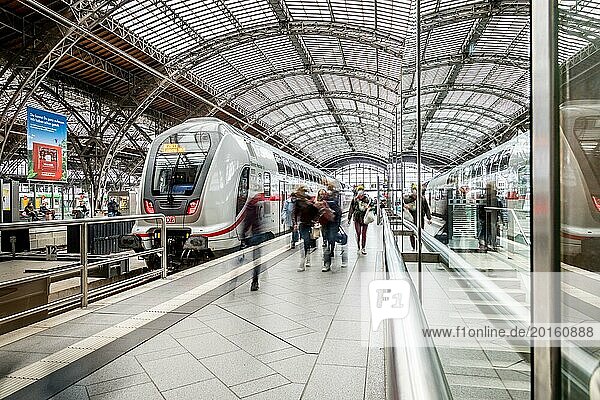 Travellers waiting for trains in a station concourse with an impressive roof  Leipzig Central Station