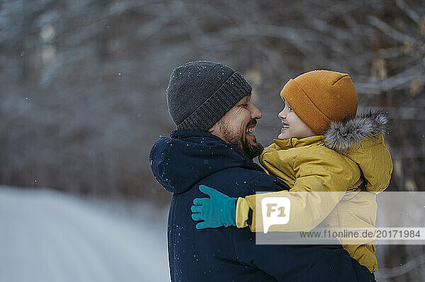Father and son having fun in winter forest