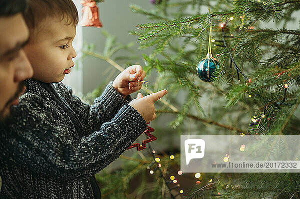 Little boy decorating Christmas tree at home