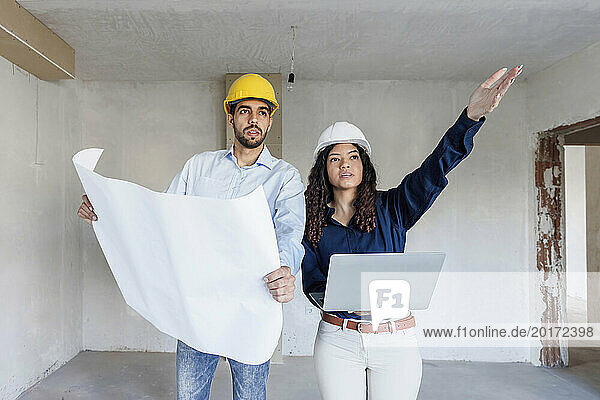 Architect gesturing and discussing with colleague at site