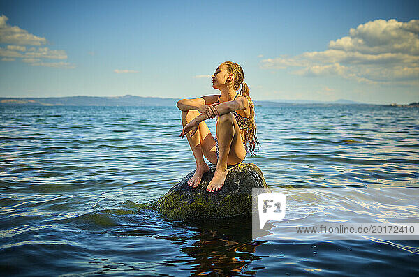 Girl sitting on rock in Lake Bolsena  Italy