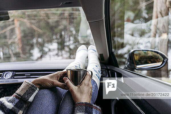 Woman holding coffee cup and sitting in car
