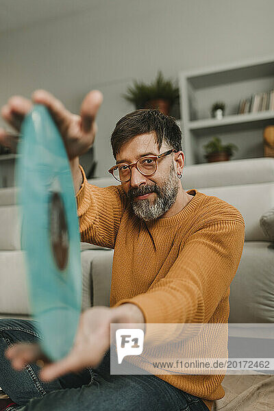 Man showing old-fashioned record sitting in living room