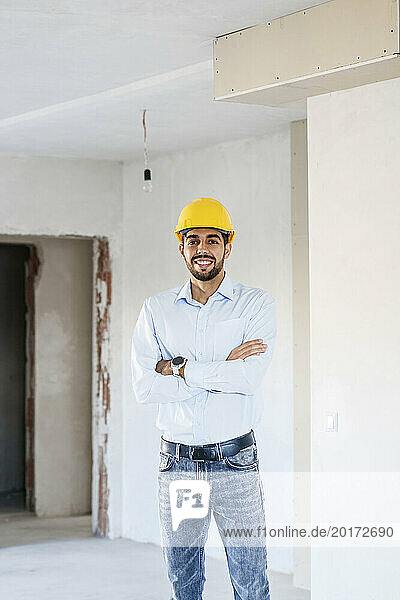 Happy architect standing with arms crossed at site