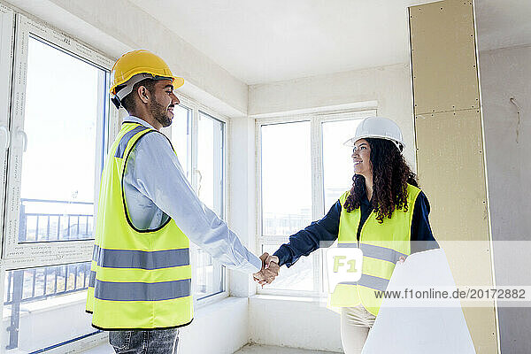 Smiling architects shaking hands at site