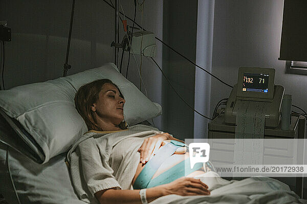 Pregnant woman resting on hospital bed in delivery room