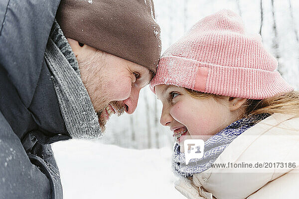 Playful father and daughter having fun in winter forest