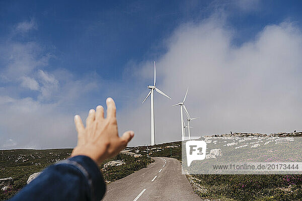 Spain  Madrid  POV of woman reaching toward wind farm turbines standing in background