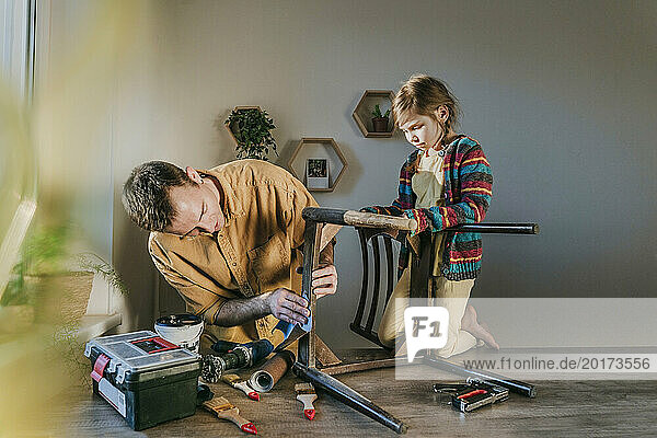 Father preparing chair with daughter at home
