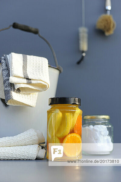 Jars of homemade cleaning products near bucket with rags