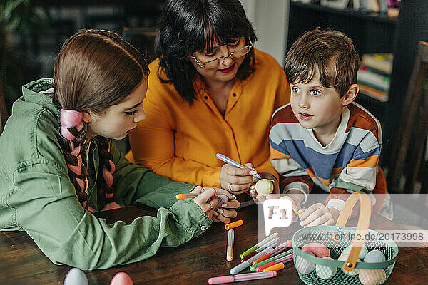 Happy grandmother with grandchildren painting Easter eggs