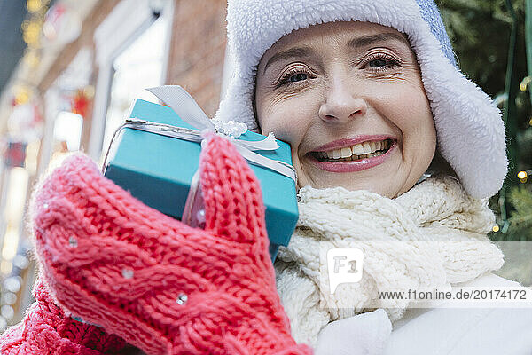 Happy woman wearing warm clothes and showing gift box