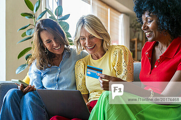 Happy senior woman doing online shopping with friends at home