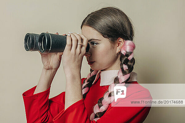Woman looking through binoculars near wall