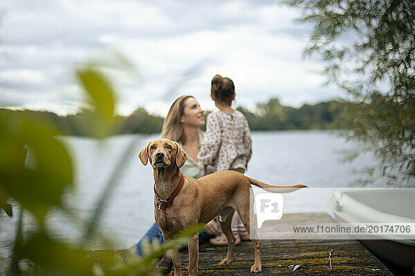 Dog near mother and daughter in front of lake