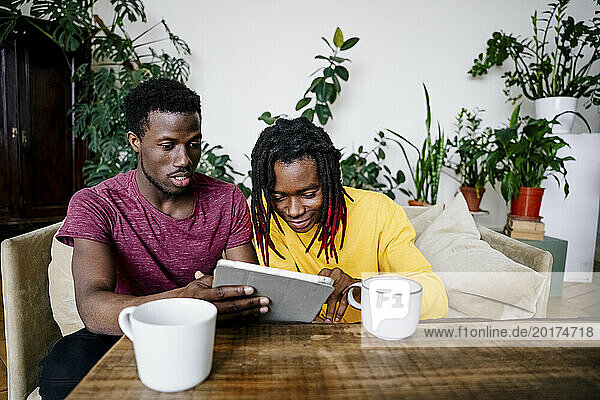 Man sharing tablet PC with friend at home
